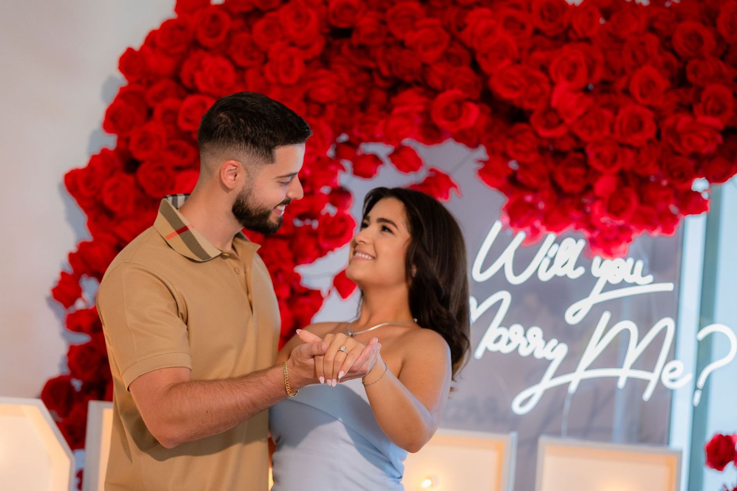 A romantic marriage proposal setup with vibrant red roses and glowing candles creating a pathway.