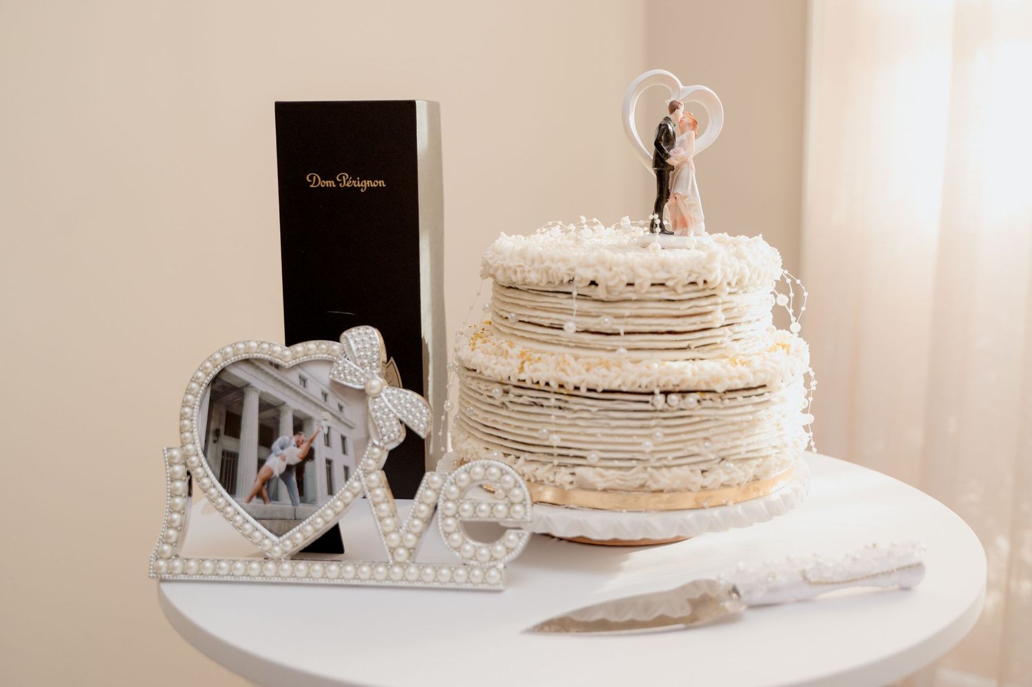 White wedding cake with delicate piping and floral decorations sits elegantly on a display table.