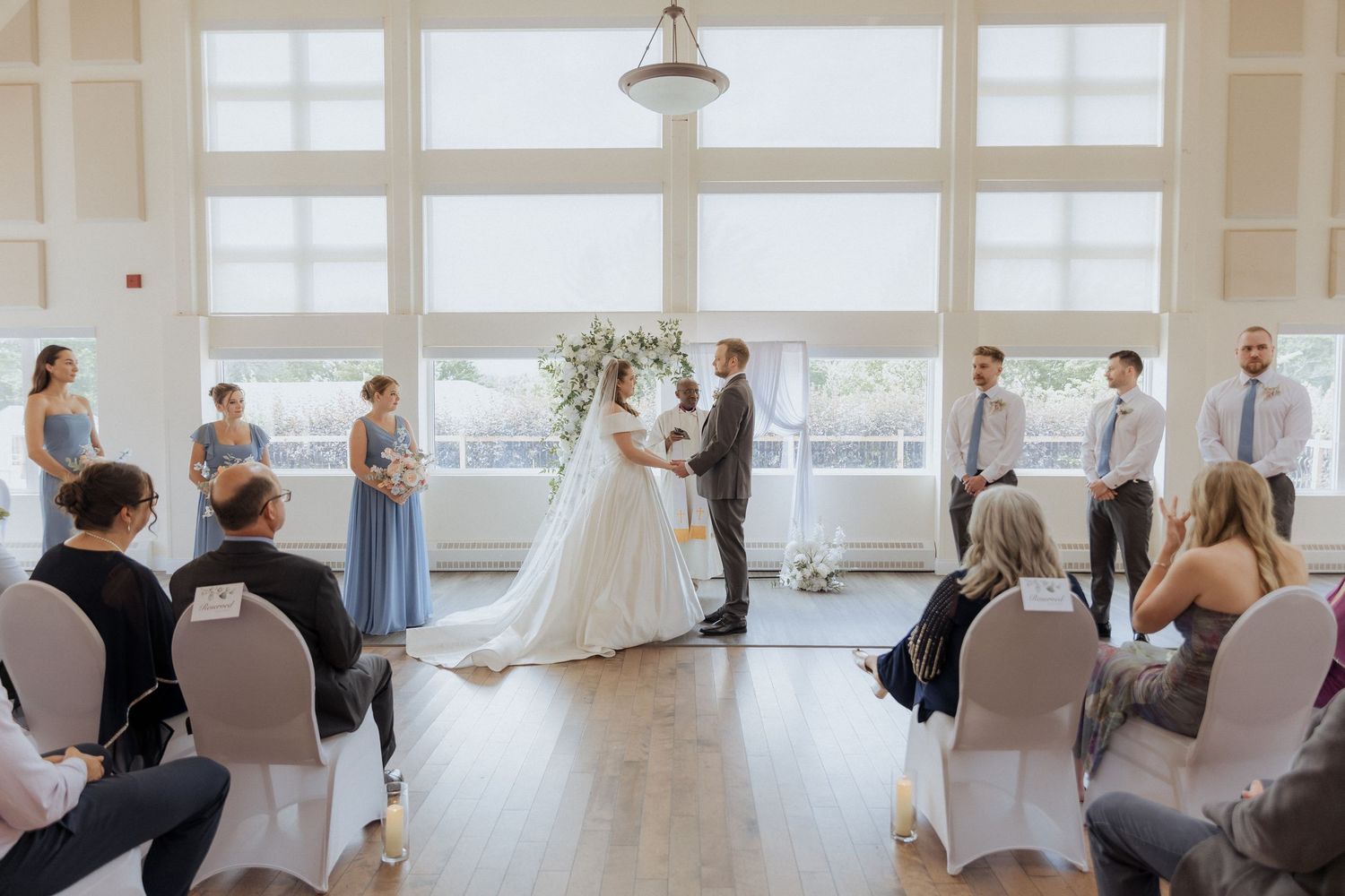 bride and groom hold hands during wedding ceremony at Douglas Hazen Centre in Oromocto wedding photography New Brunswick wedding packages
