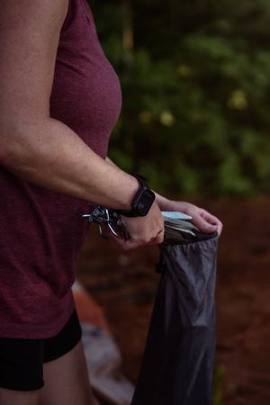 A person in a burgundy shirt demonstrates rolling and securing the waistband of dark-colored clothing.