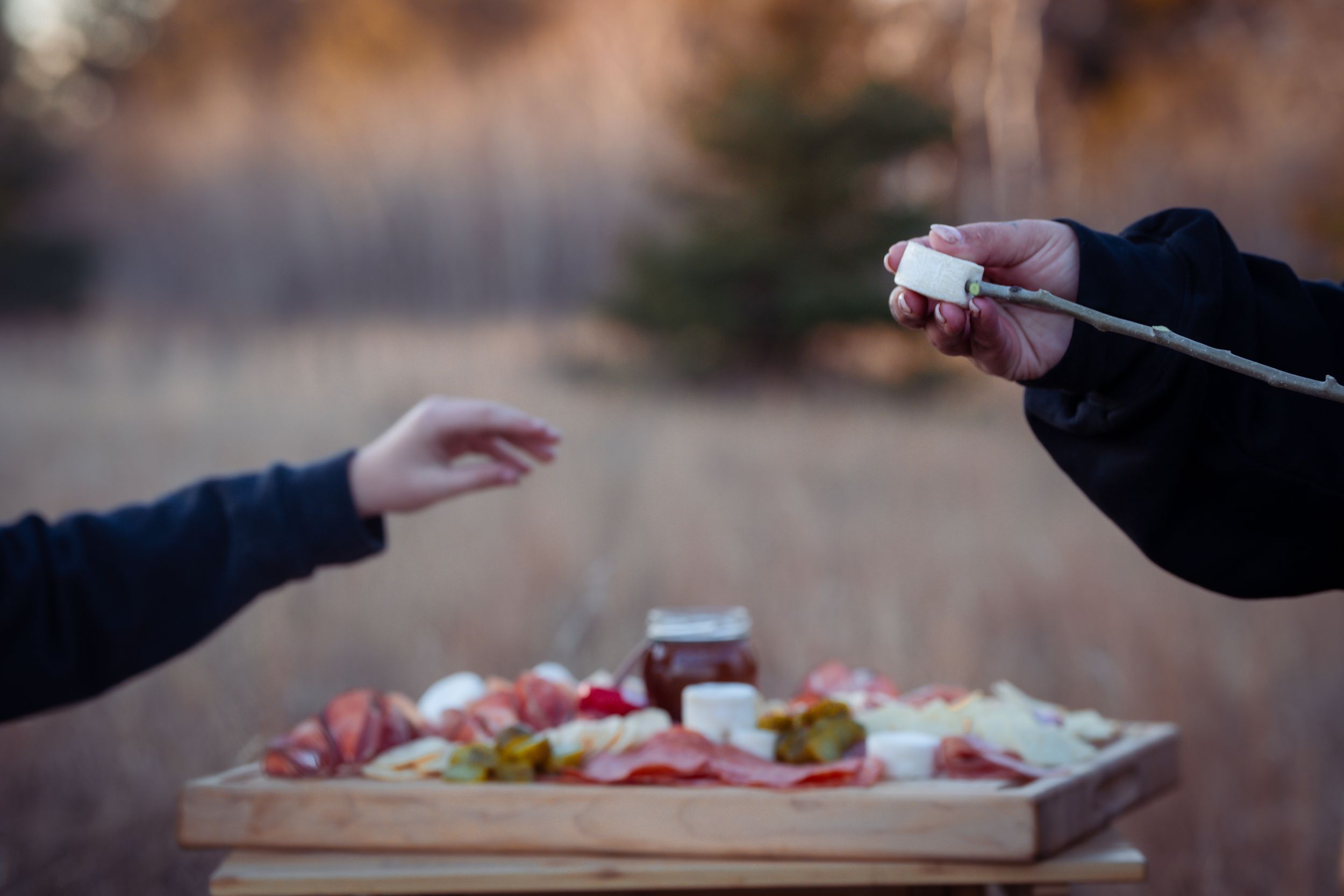 Someone opens containers of colorful sushi takeout arranged on a dark wooden table.