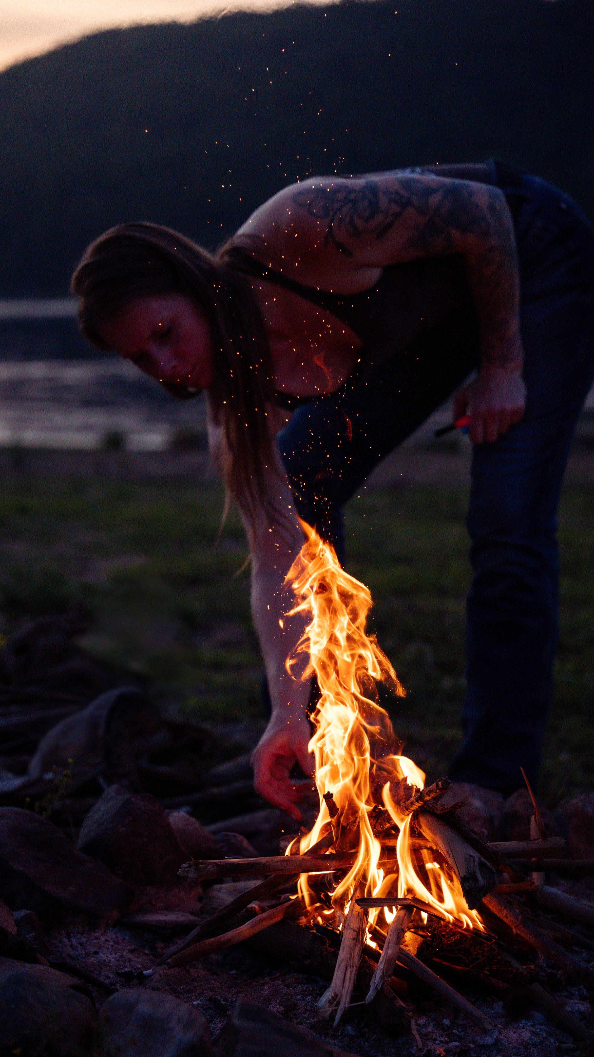 Time-lapse sequence showing a campfire starting and growing into bright orange flames at dusk.