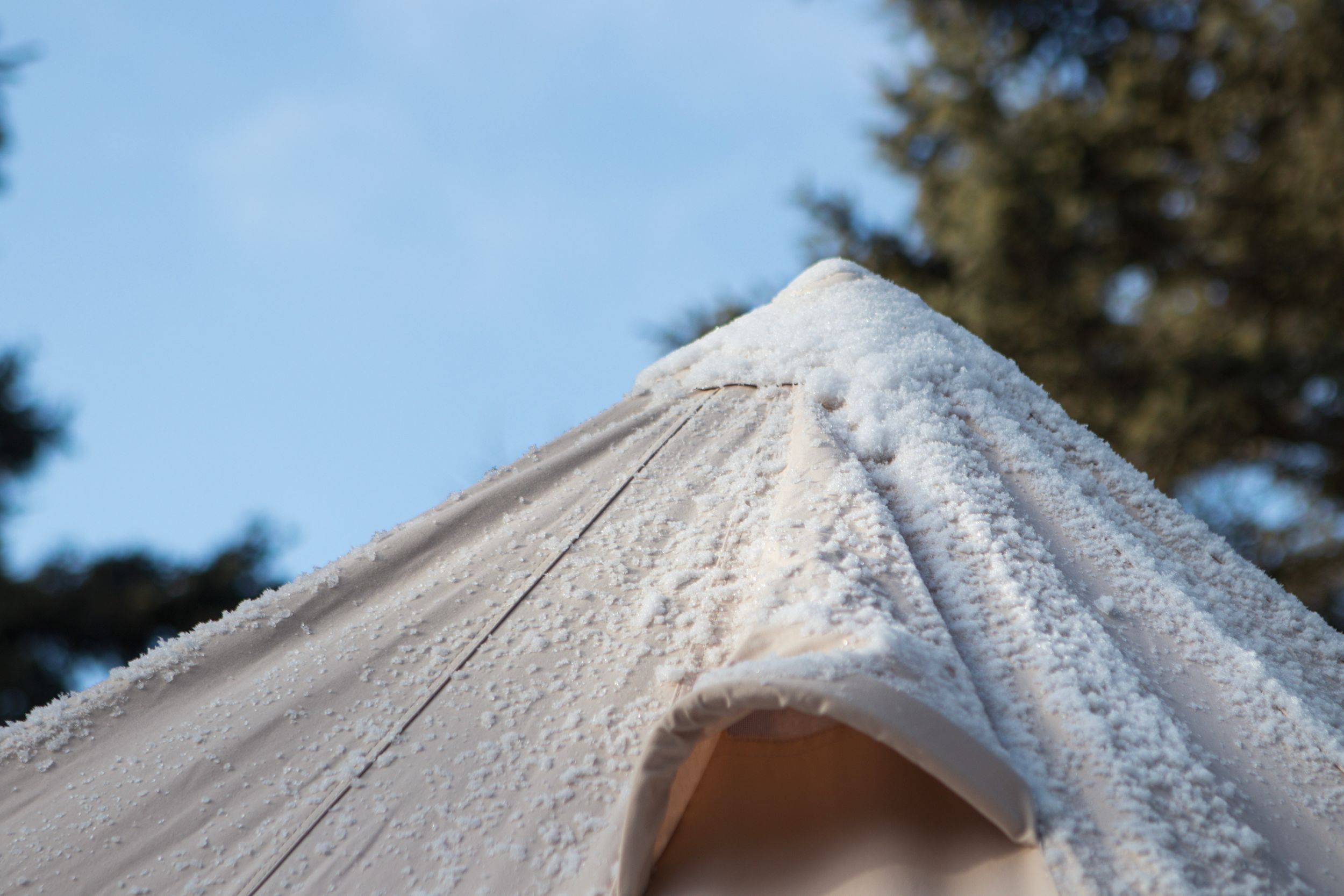 Close-up view of fresh snow covering a gutter and downspout on a residential roofline.