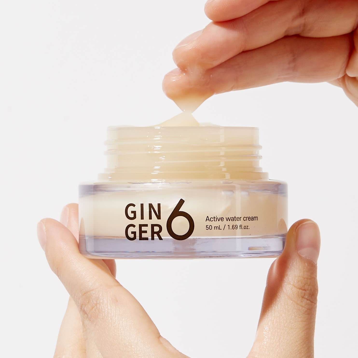 Hands demonstrating texture of Ginger 6 moisturizing cream product.