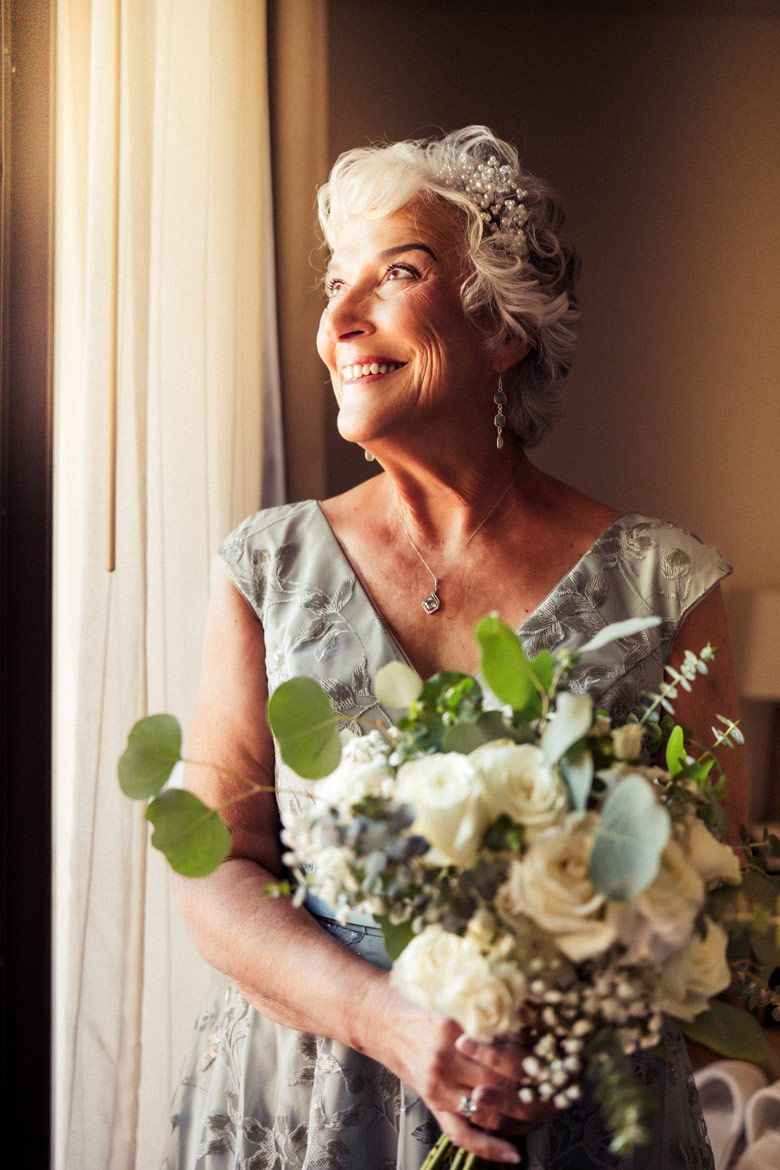 A soft, natural light portrait by a window with a white and green wedding bouquet.