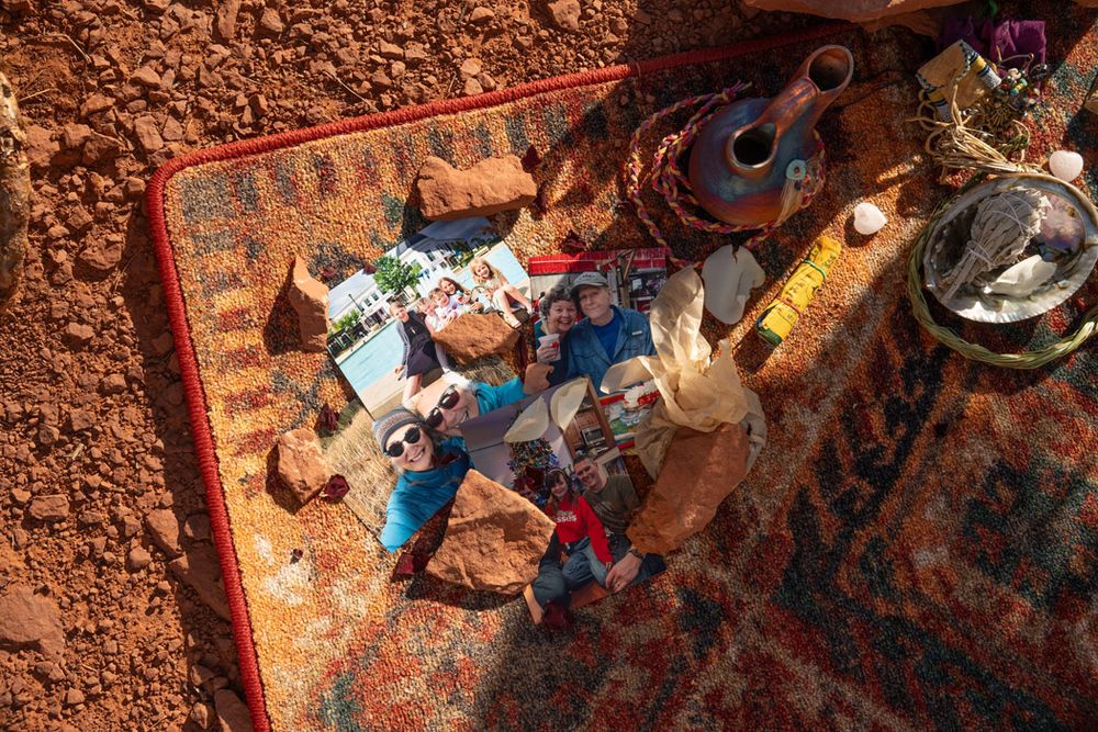 Scattered wedding details and decorations laid out on a Sedona red textured surface in natural lighting.