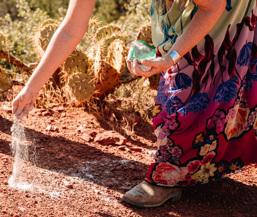 Close-up of floral dress fabric and shoes on Sedona red desert soil.
