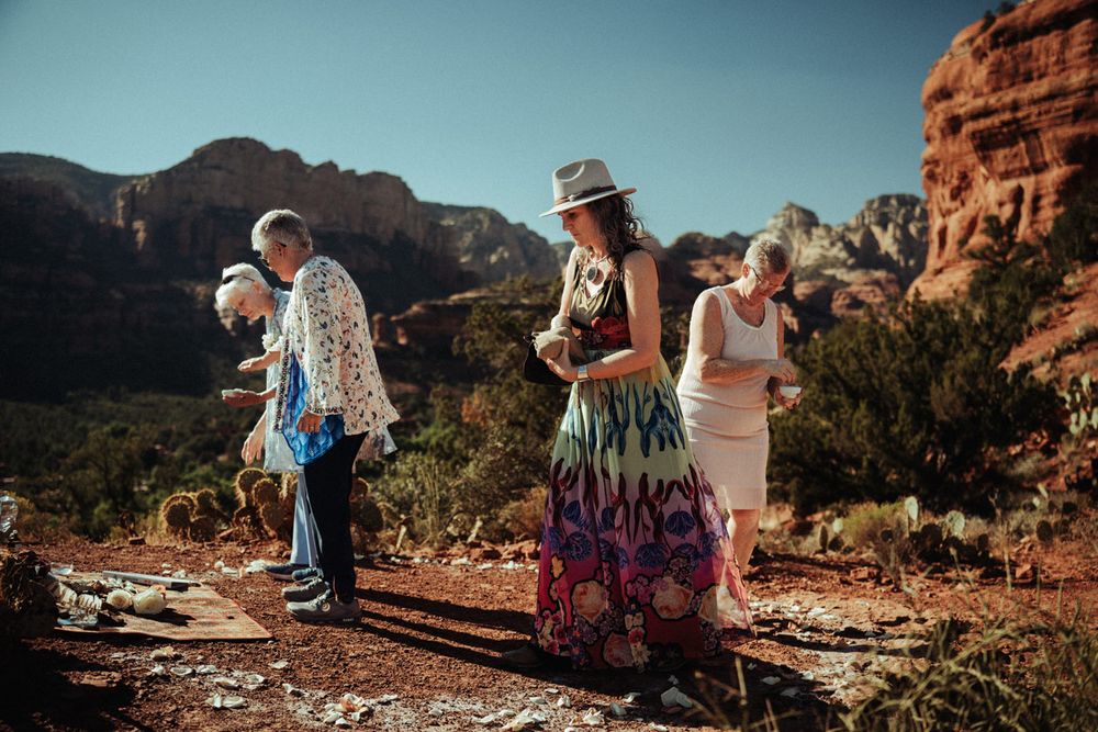 People walking along a scenic desert trail with Sedona red rock formations in the background.