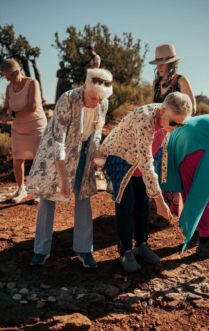 A group exploring the red rocks of Sedona on a sunny afternoon wearing flowing dresses and casual attire.