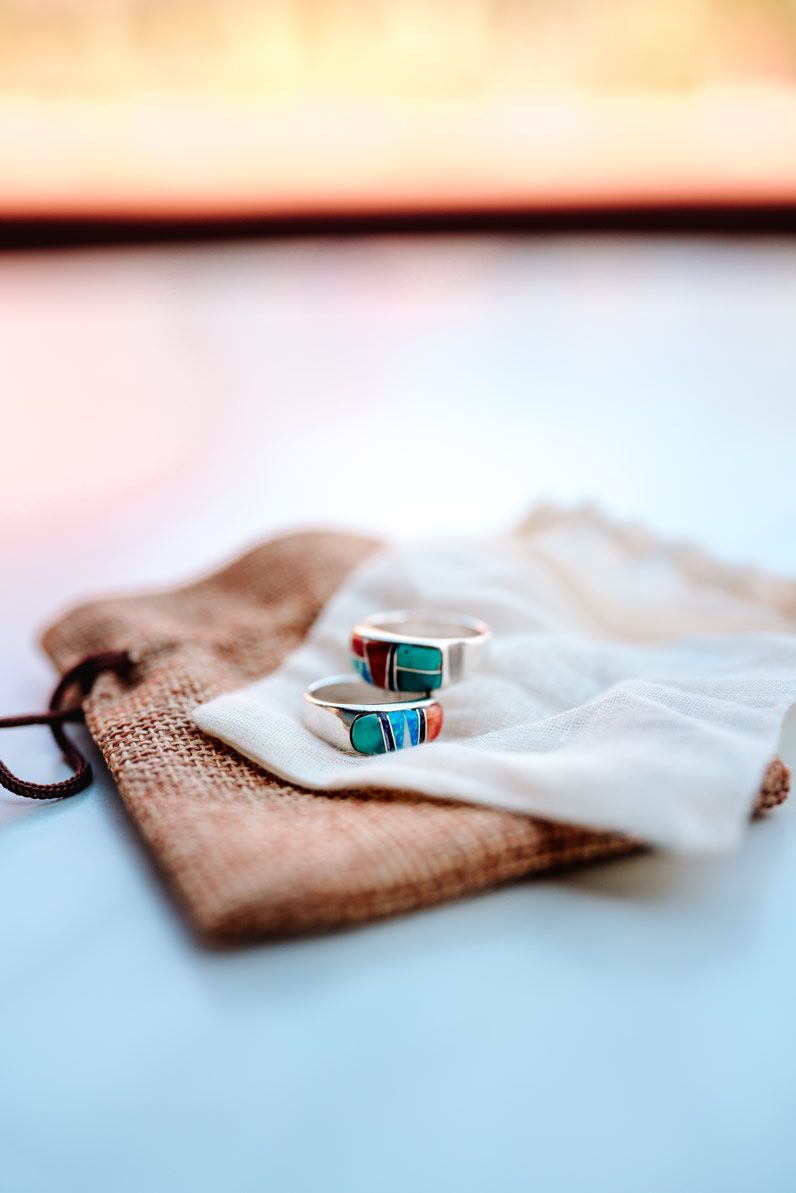 Turquoise inlay rings displayed on a burlap and white fabric background.