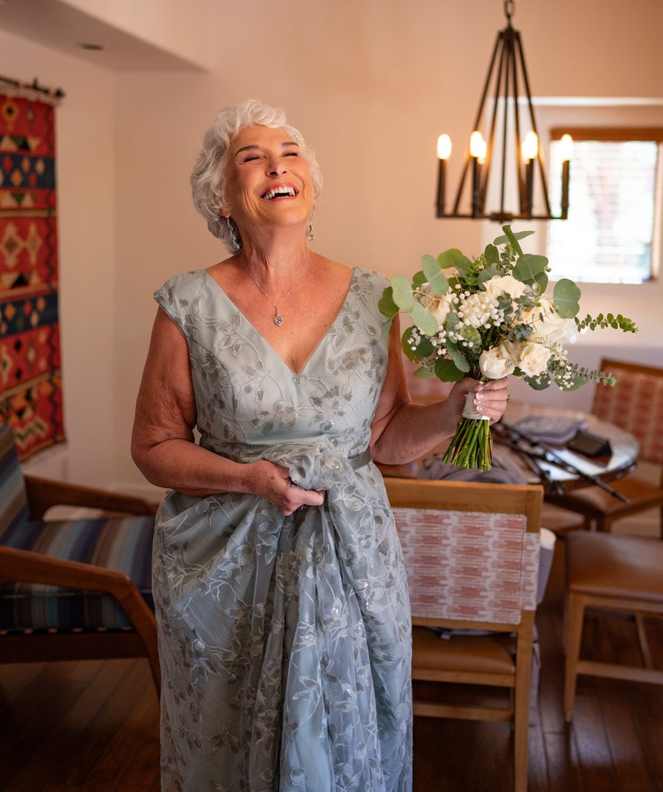 Candid moment of joy while holding wedding bouquet in naturally lit indoor setting.