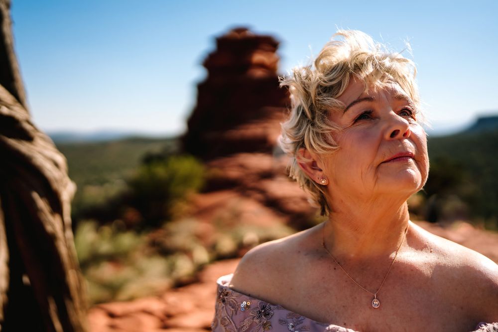 Close-up portrait in desert setting with Sedona red rock formations and blue sky in background.
