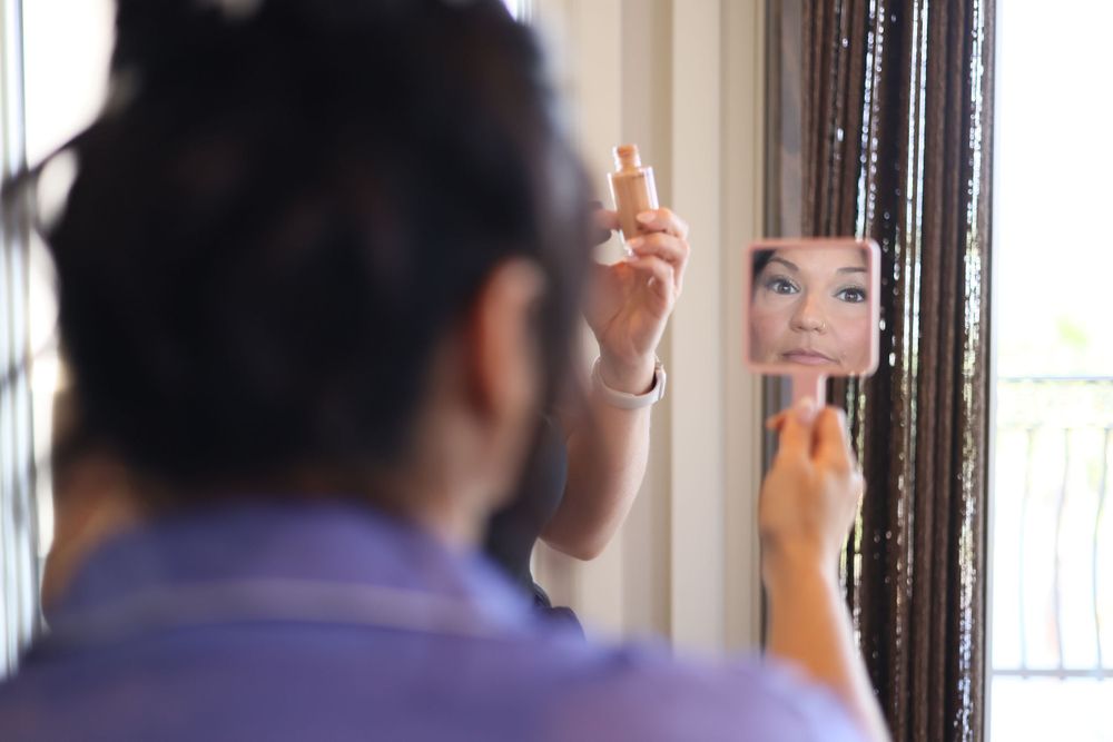 Getting ready moment reflected in a mirror by a window.