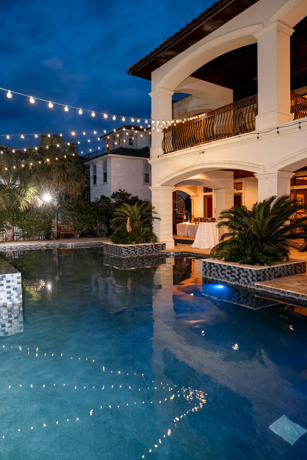 Luxurious villa with illuminated pool and string lights creating a romantic evening ambiance.