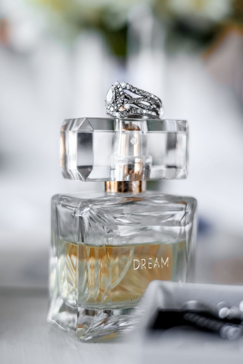 A crystal perfume bottle labeled 'Dream' with a ring placed on top.
