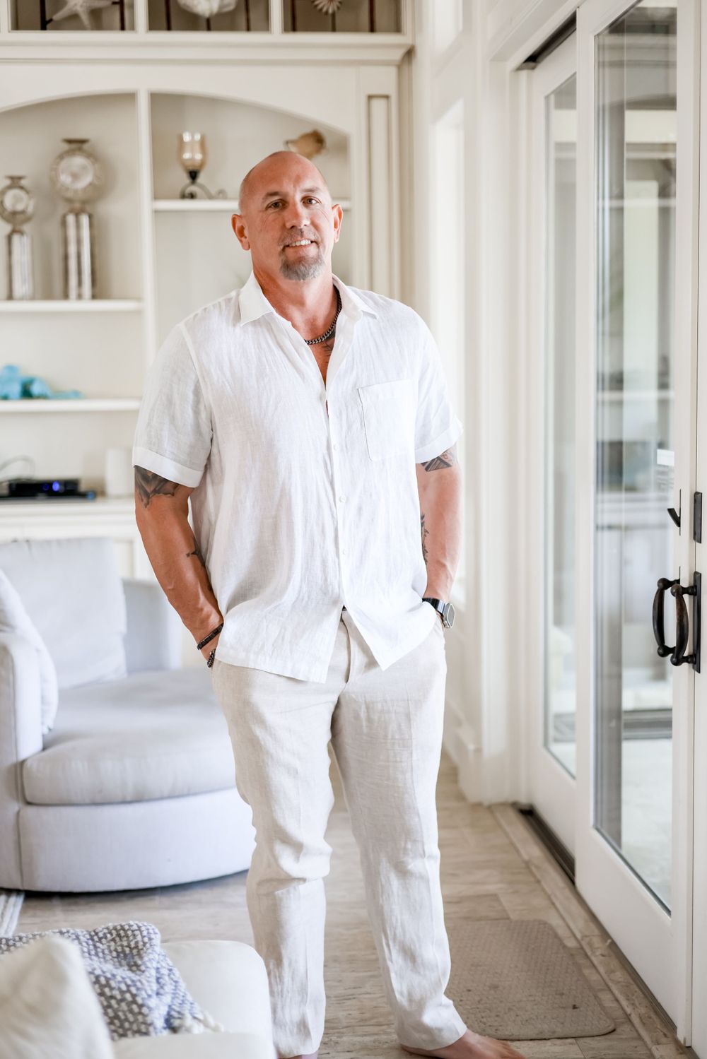 Person in all-white casual attire standing in modern coastal-style living room.