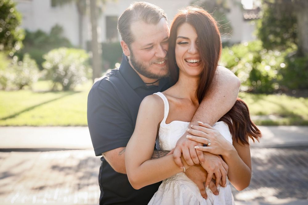 Romantic couple embracing and laughing together in sunlit outdoor setting.