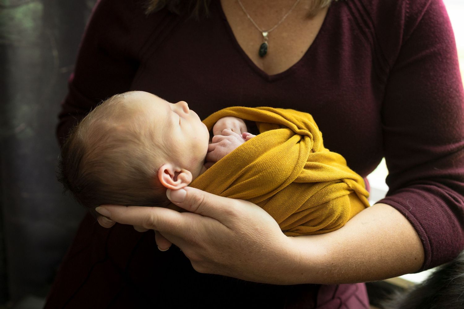 A tender moment captured in low light showing a sleeping infant in mustard yellow clothing.