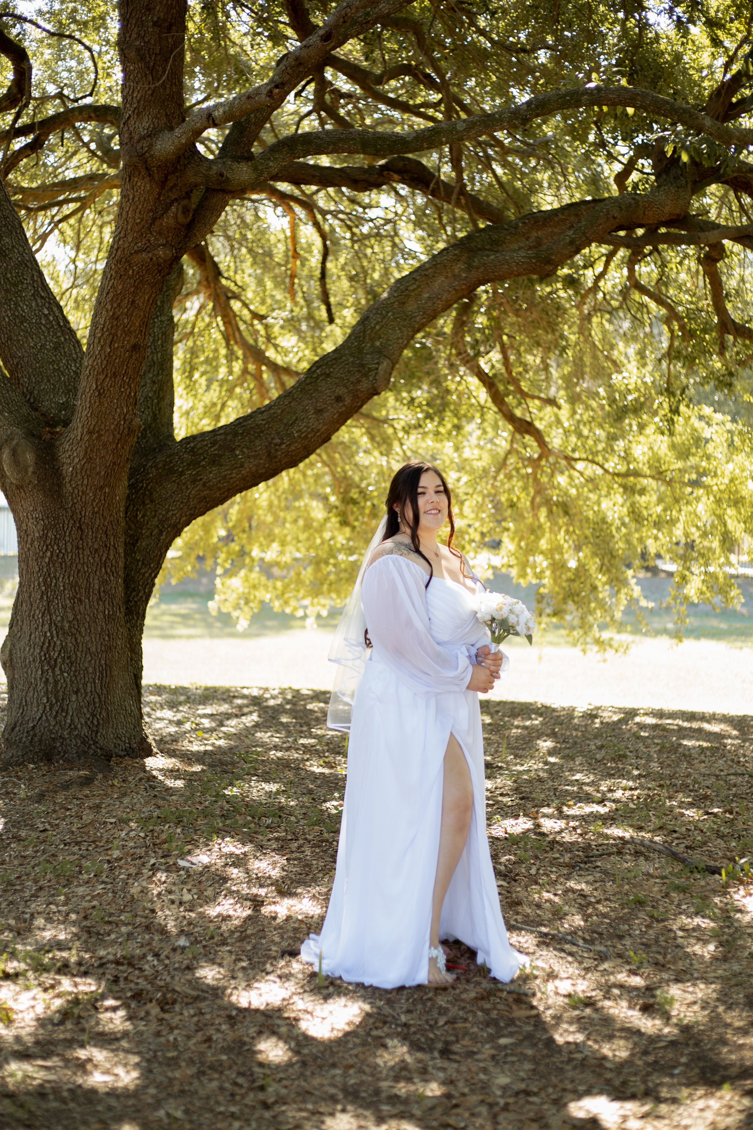 A elegant bridal portrait featuring a white dress against the backdrop of a majestic oak tree.