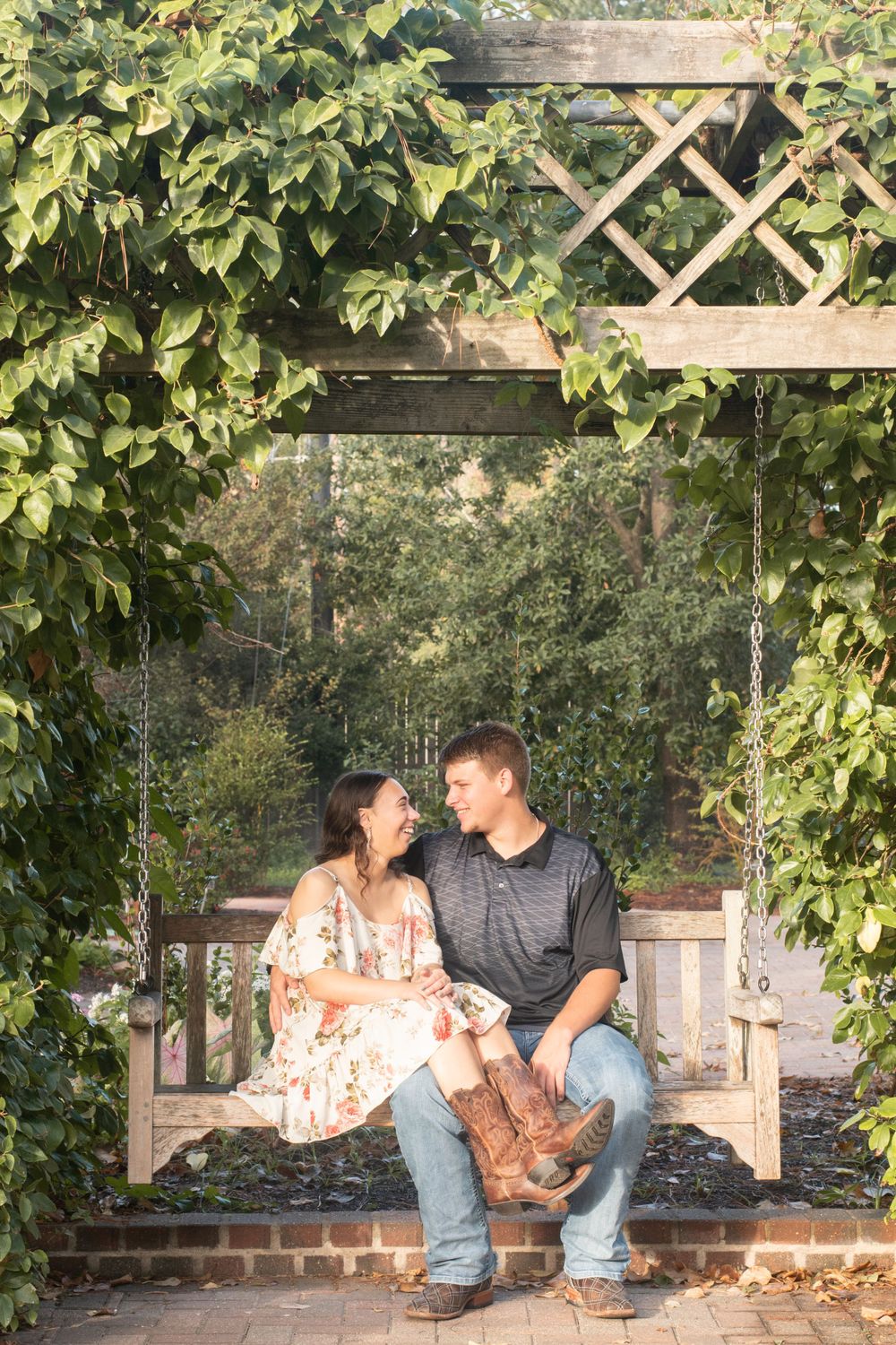 A couple sitting together on a garden swing surrounded by lush green vines.