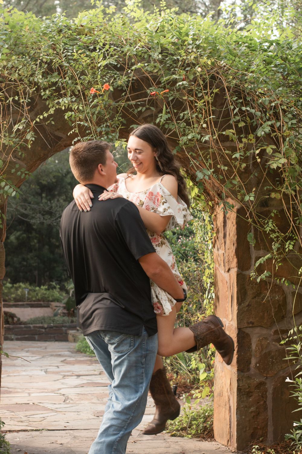 Romantic moment captured in garden archway with flowering vines.