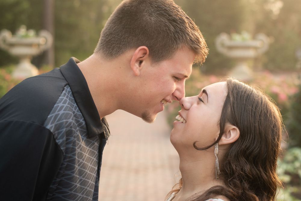 Close-up intimate moment shared between couple in garden setting at sunset.