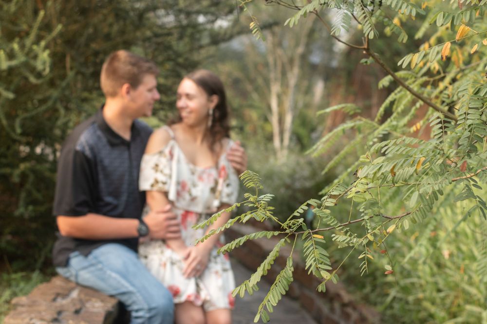 Soft focus photo of a couple sitting together outdoors surrounded by greenery.