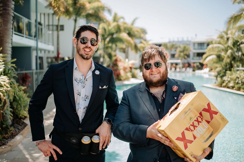 Two people pose casually by a resort pool, one holding a takeout box.