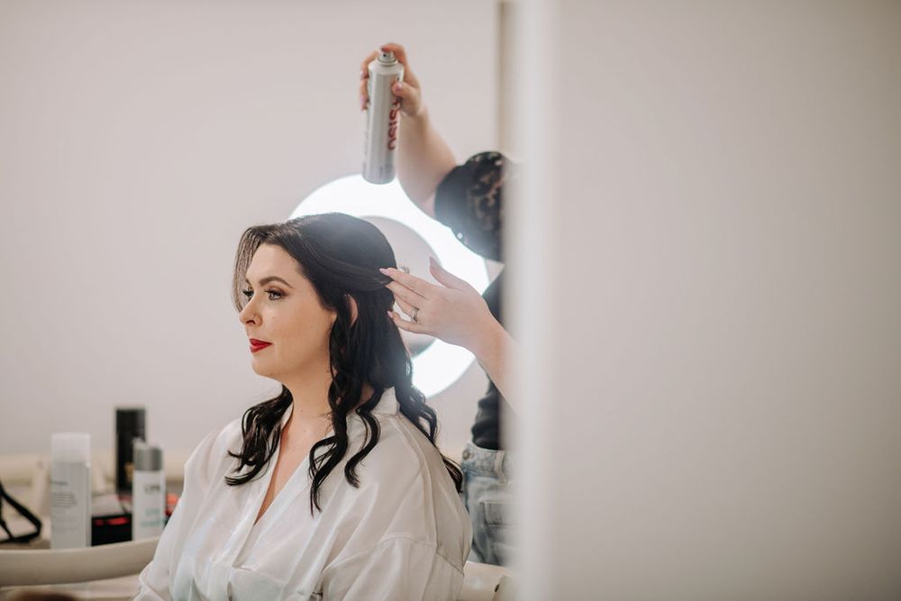 Behind-the-scenes wedding preparation in a brightly lit dressing room.