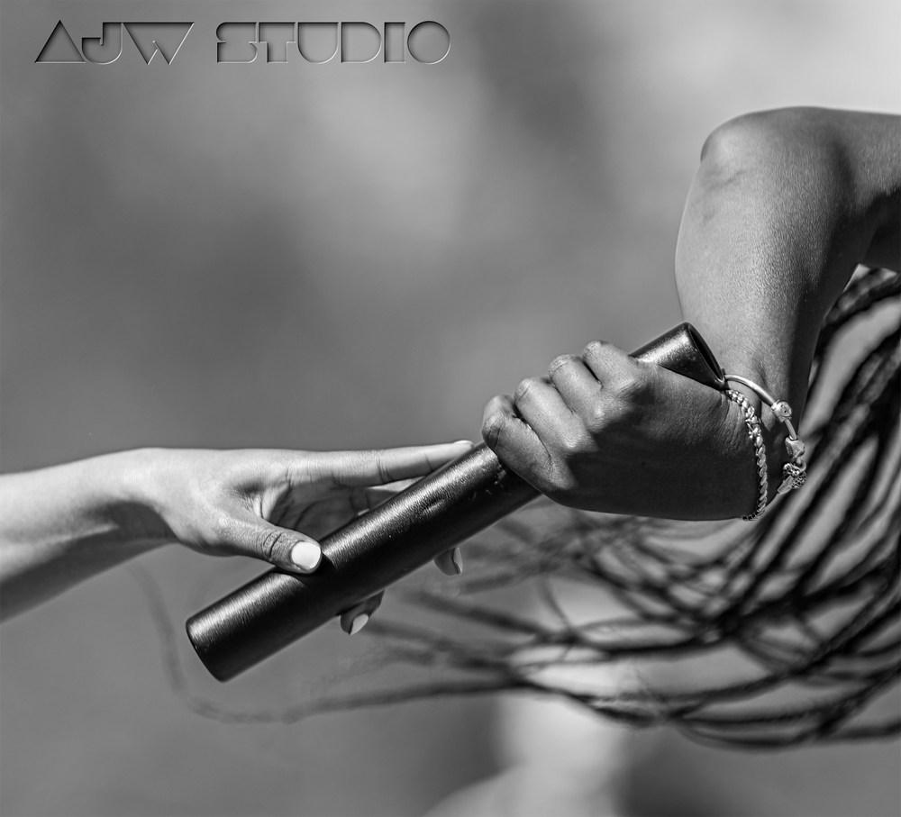 Black and white close-up of hands passing a relay baton during a race.
