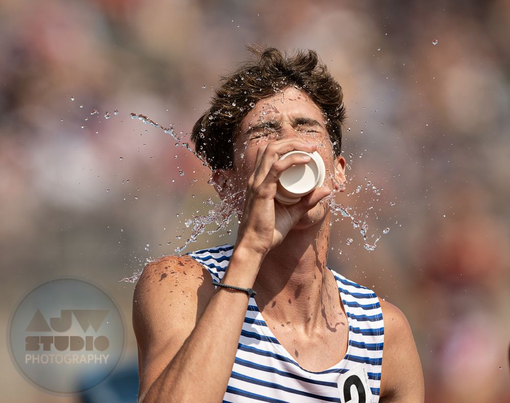 Track athlete splashes water while drinking during competition.