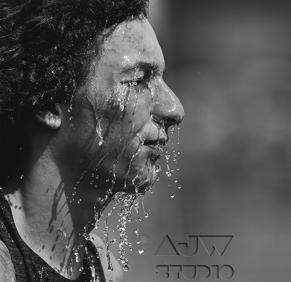 Dramatic black and white athletic portrait showing water droplets cascading down an athlete's face in profile.