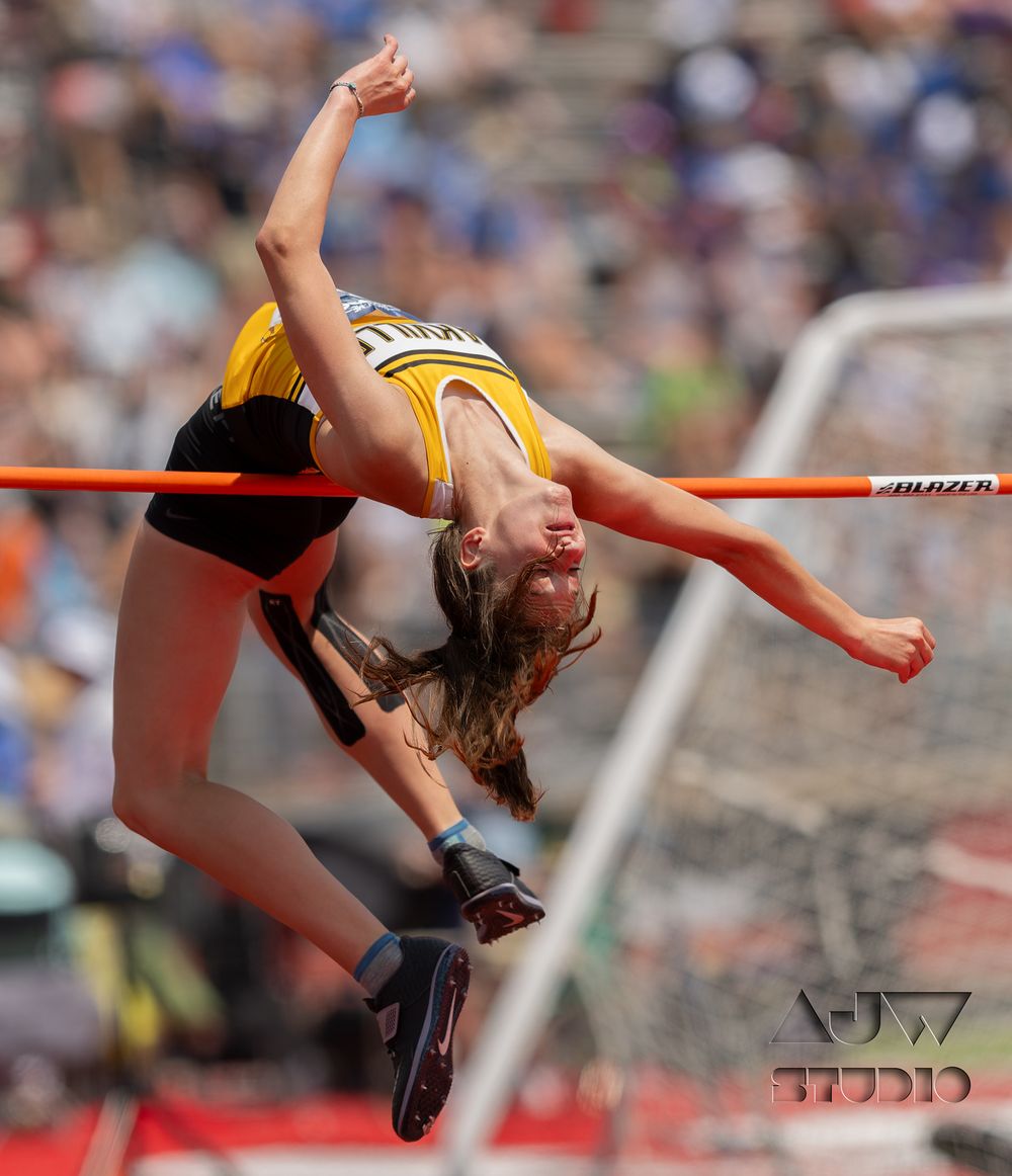 High jumper arches backwards over bar during track and field competition.