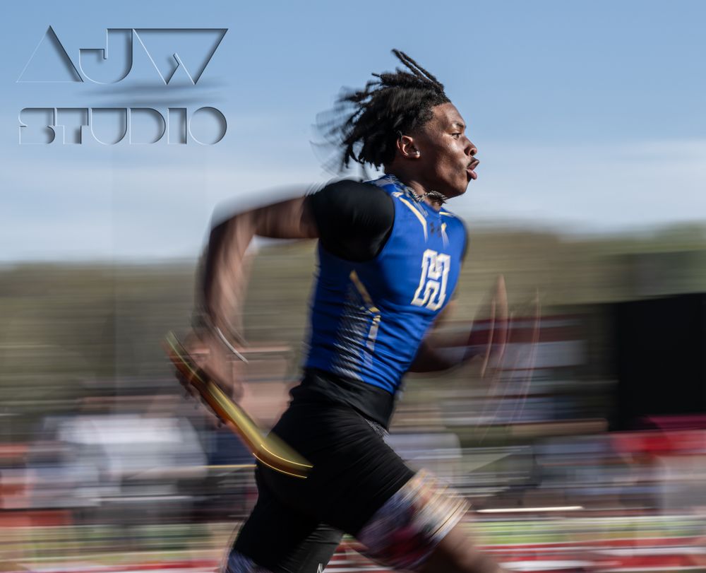 Track athlete in blue uniform sprints at high speed during competition.