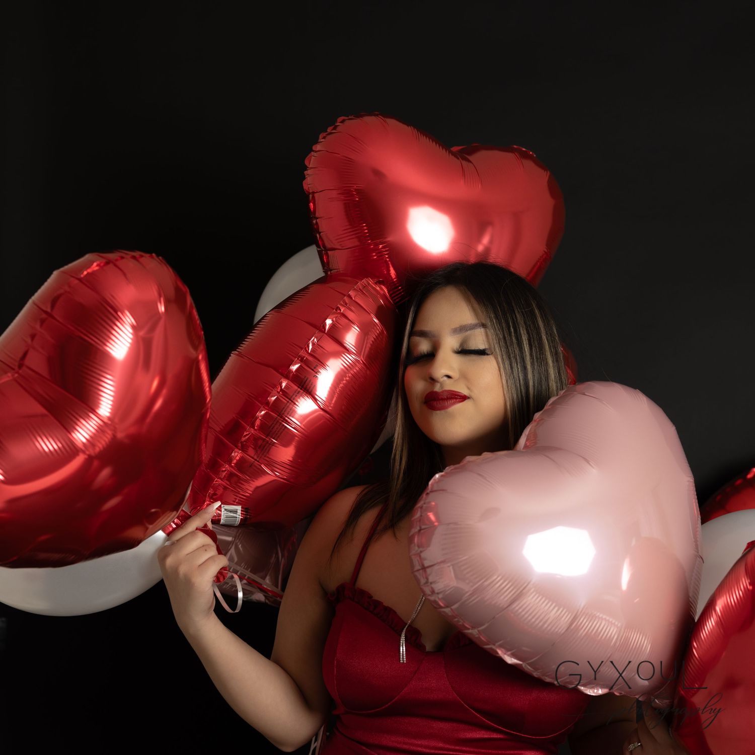 Glamorous Valentine's setting with metallic heart balloons and red attire.
