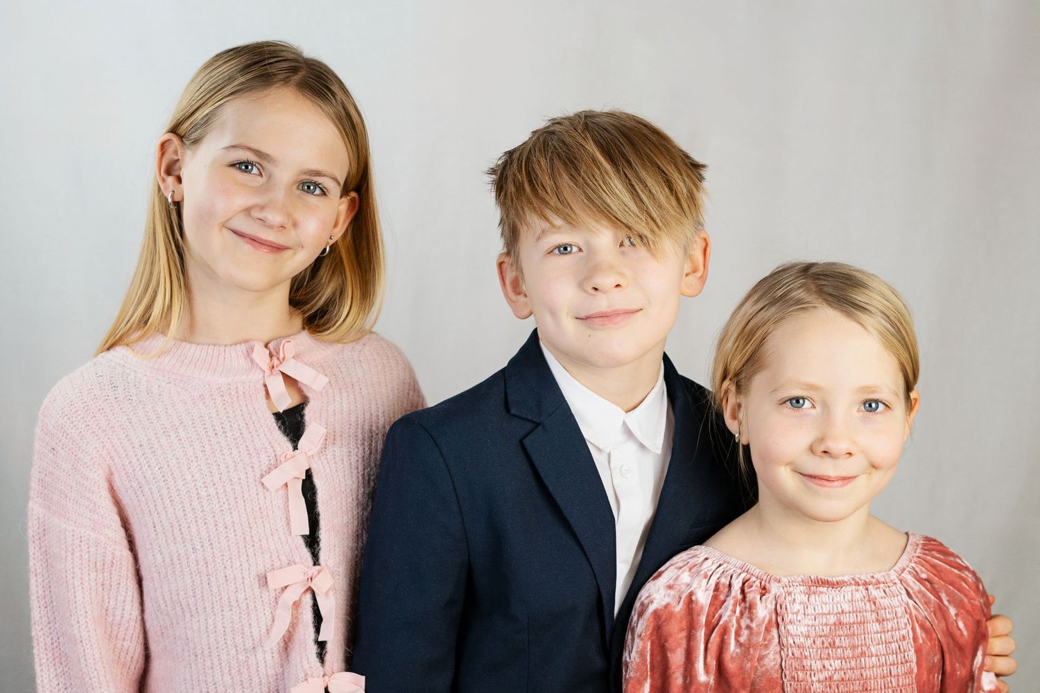 Familj som bär koordinerade rosa och svarta kläder poserar tillsammans för en formell porträttsession. - Fotograf Emma Matkoski