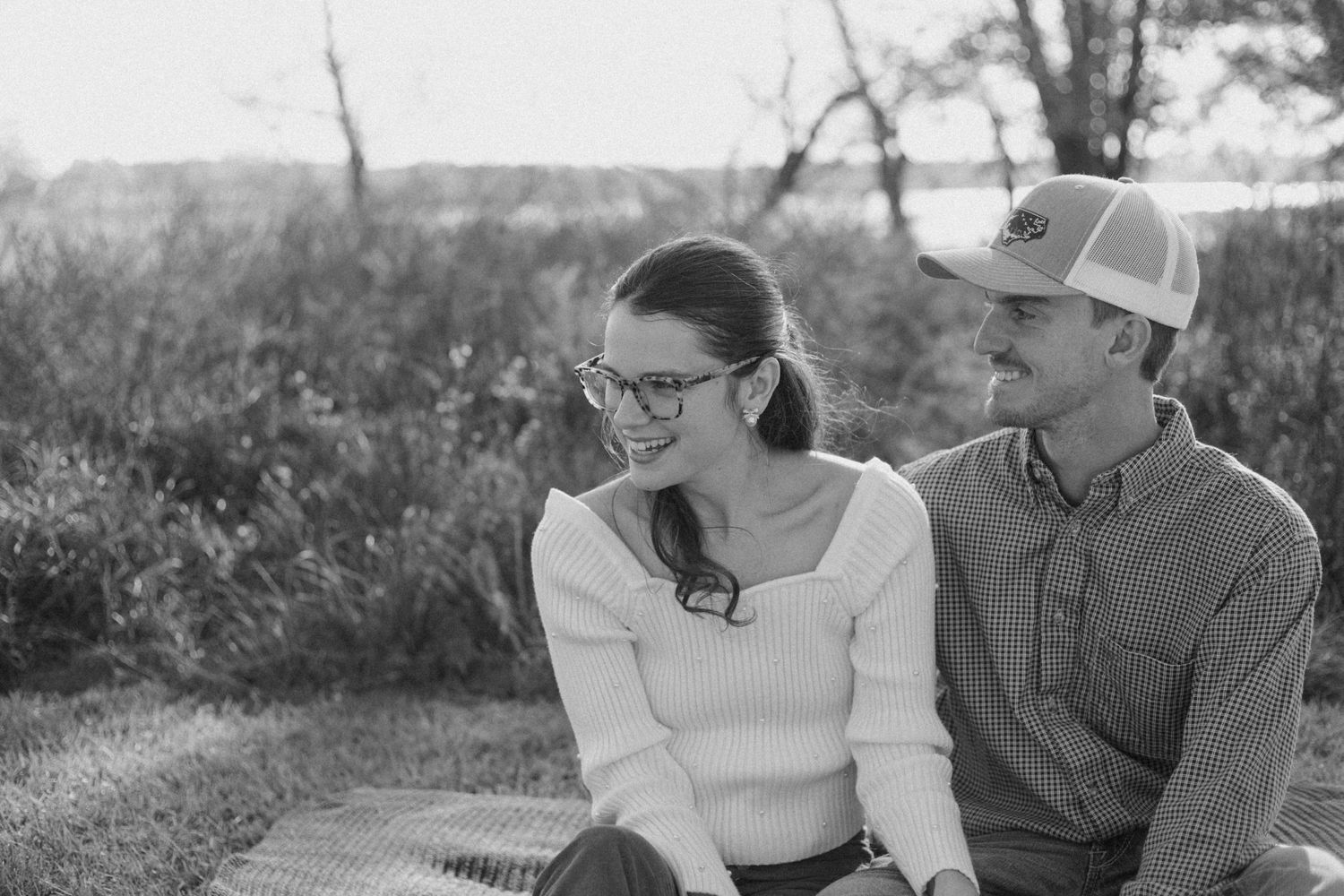 A couple sitting together outdoors in casual autumn attire.