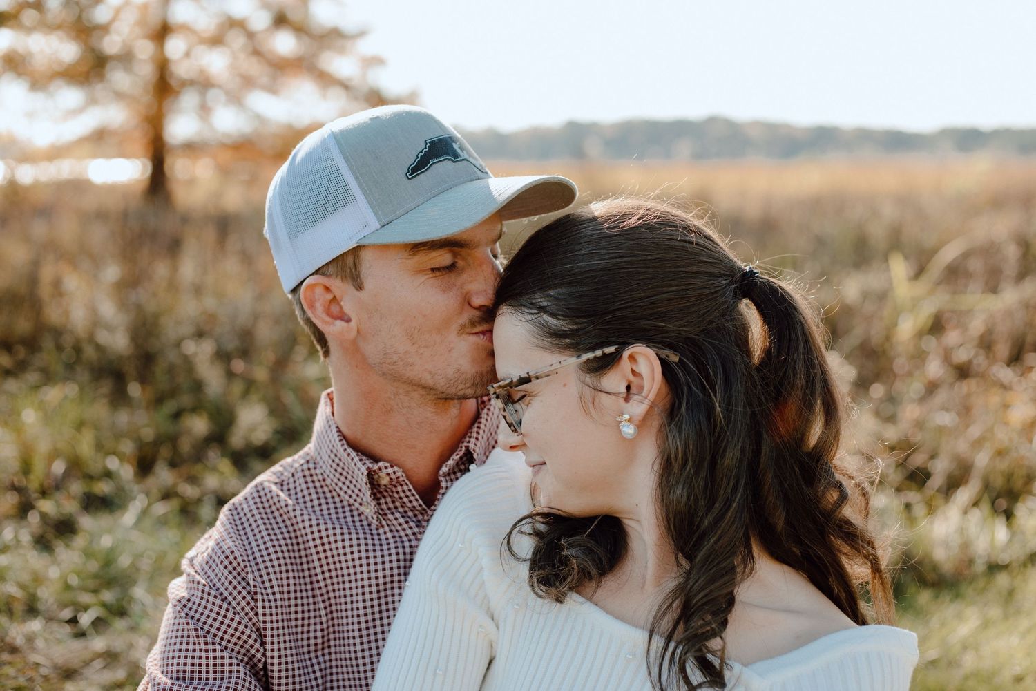 An intimate moment between a couple wearing casual attire against a natural backdrop.