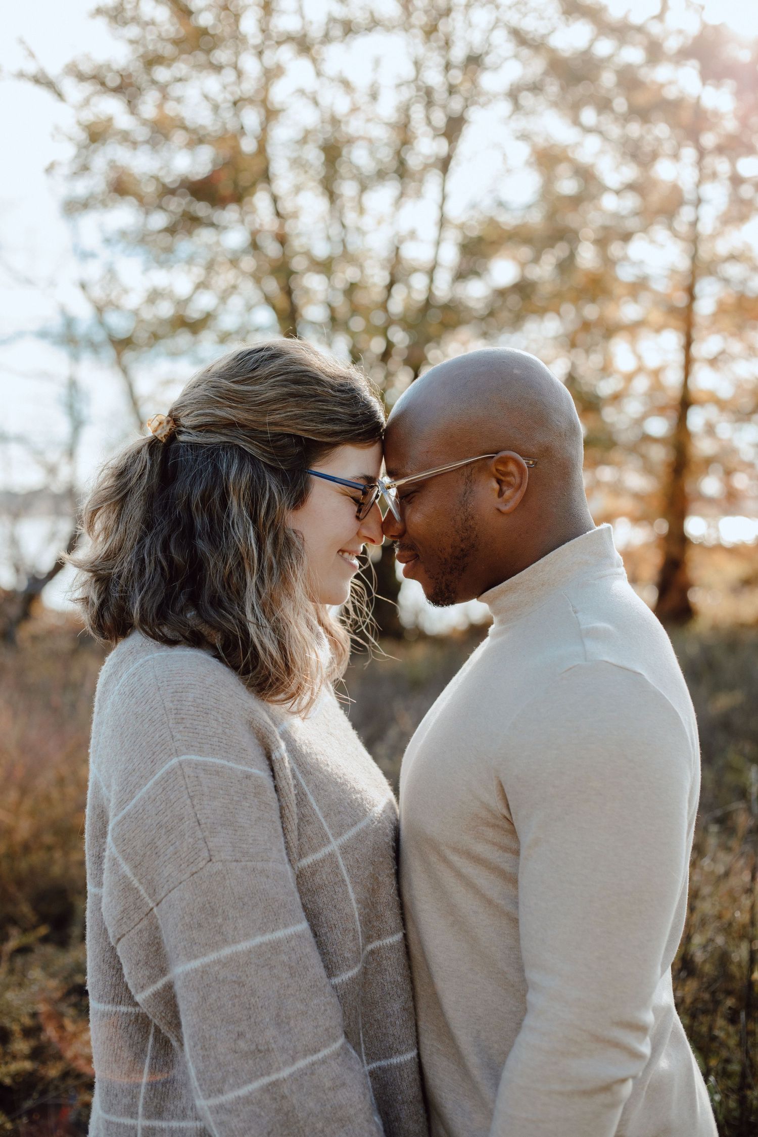 A loving couple in cozy sweaters shares an intimate moment during golden hour.