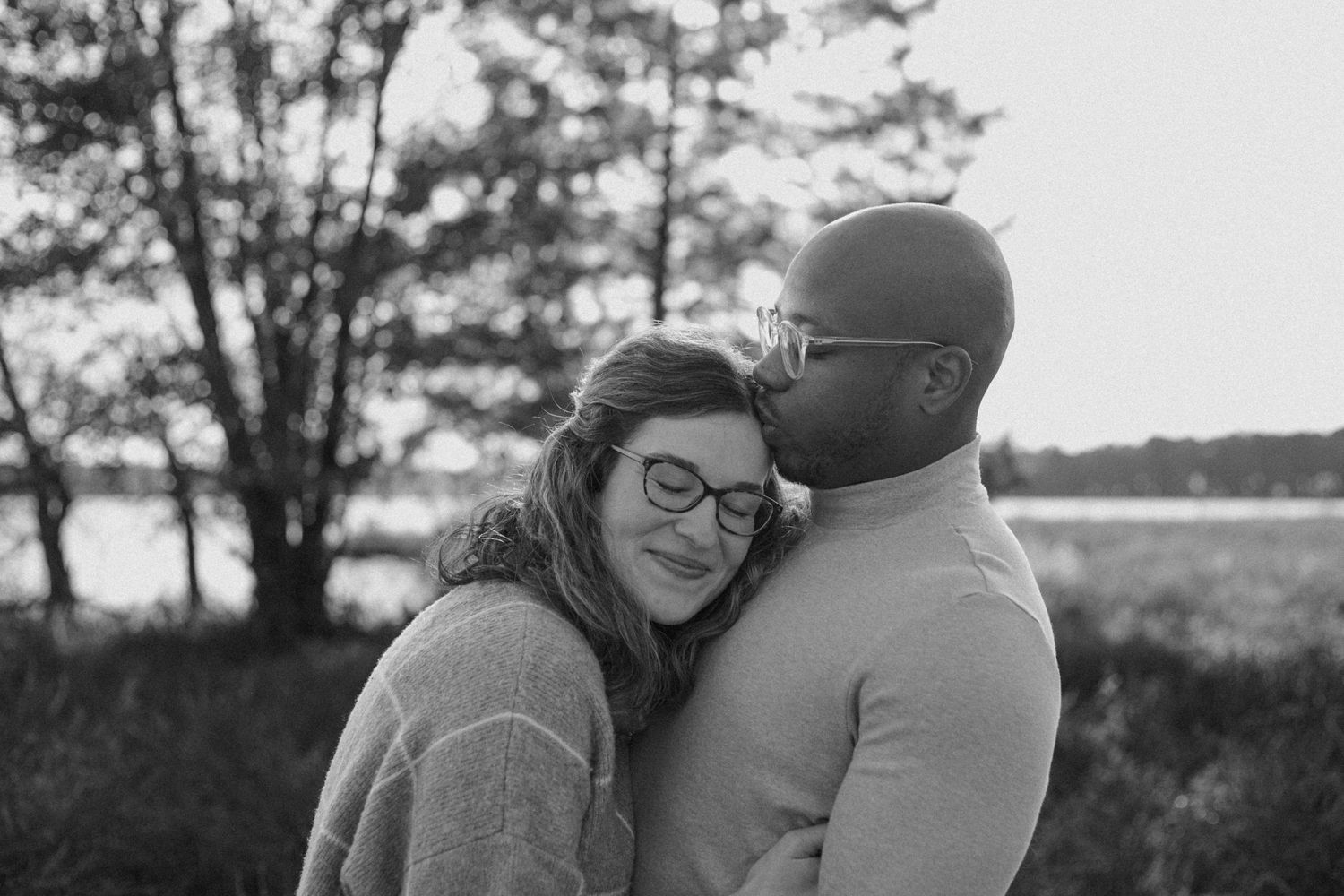 A couple in warm sweaters embraces during an intimate black and white portrait session.