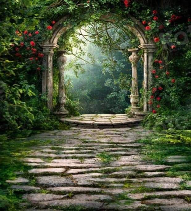 Stone archway covered in red climbing roses leading to a misty garden path.