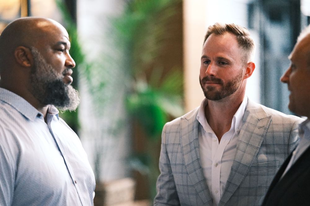 Three people engaged in professional conversation at upscale indoor event.