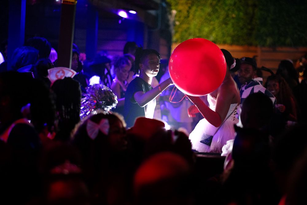 Crowd at nightclub with red balloon visible in dark lighting.
