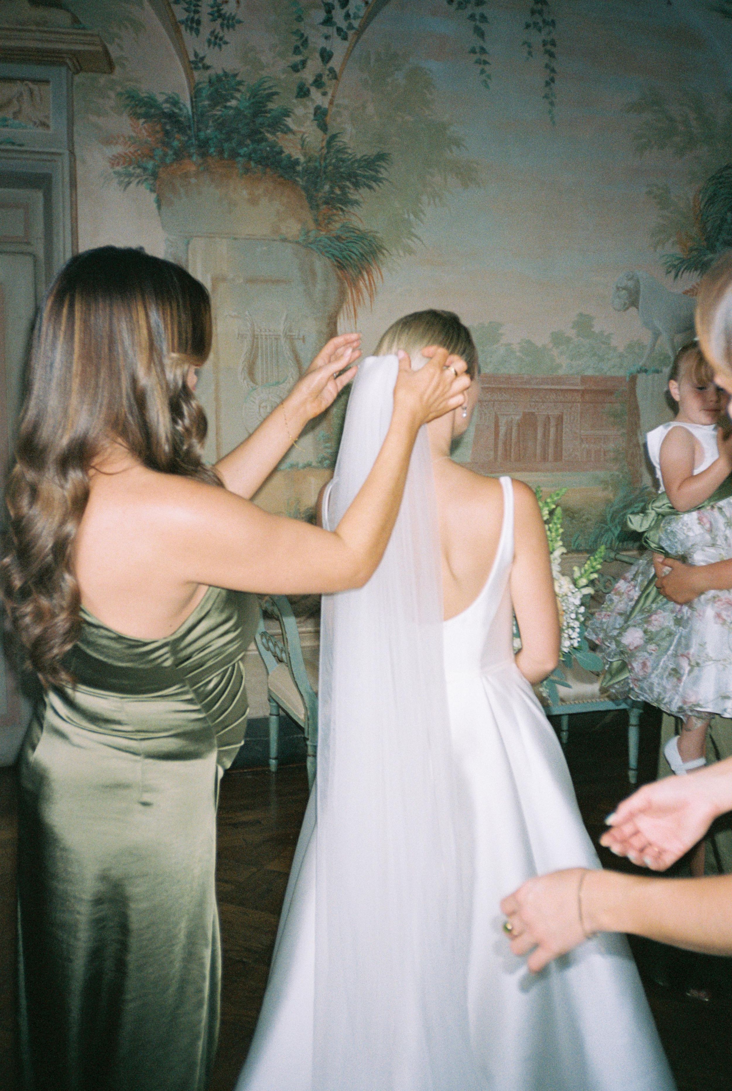 Wedding preparations showing a white dress being adjusted in an elegantly decorated room.