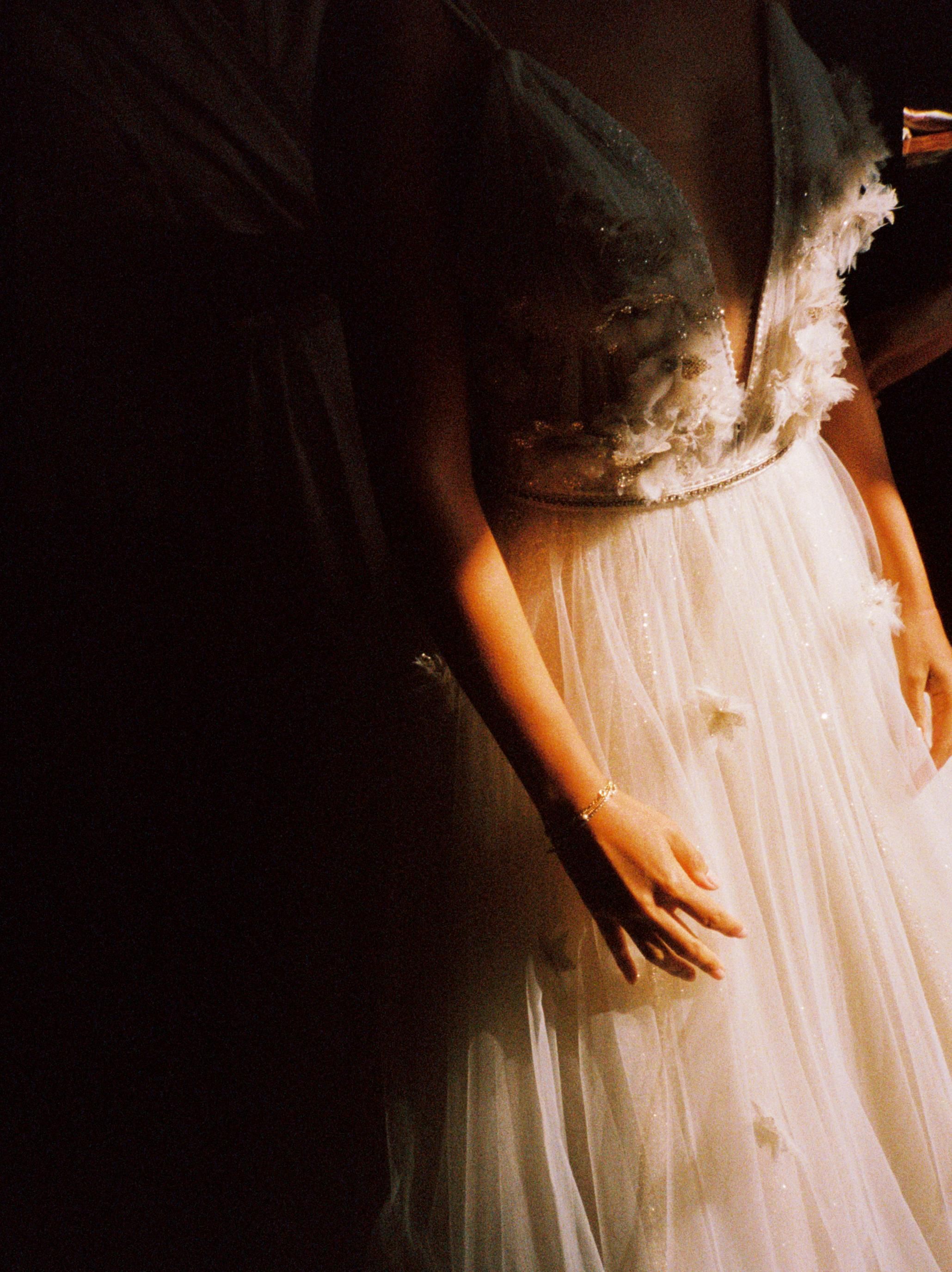 Close-up detail of a delicate white wedding dress with lace and tulle fabric.