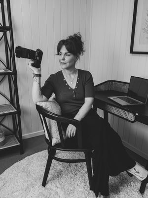 A person in a black dress sits on a vintage wooden chair against a light colored wall in a series of poses.