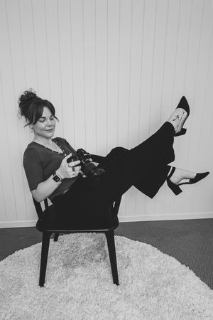 A sequence of four photos shows someone in black clothing reclining playfully across a modern chair against a white wall.