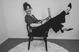 A black and white photo series shows someone in dark clothing sitting in various poses on a wooden chair against a white wall.
