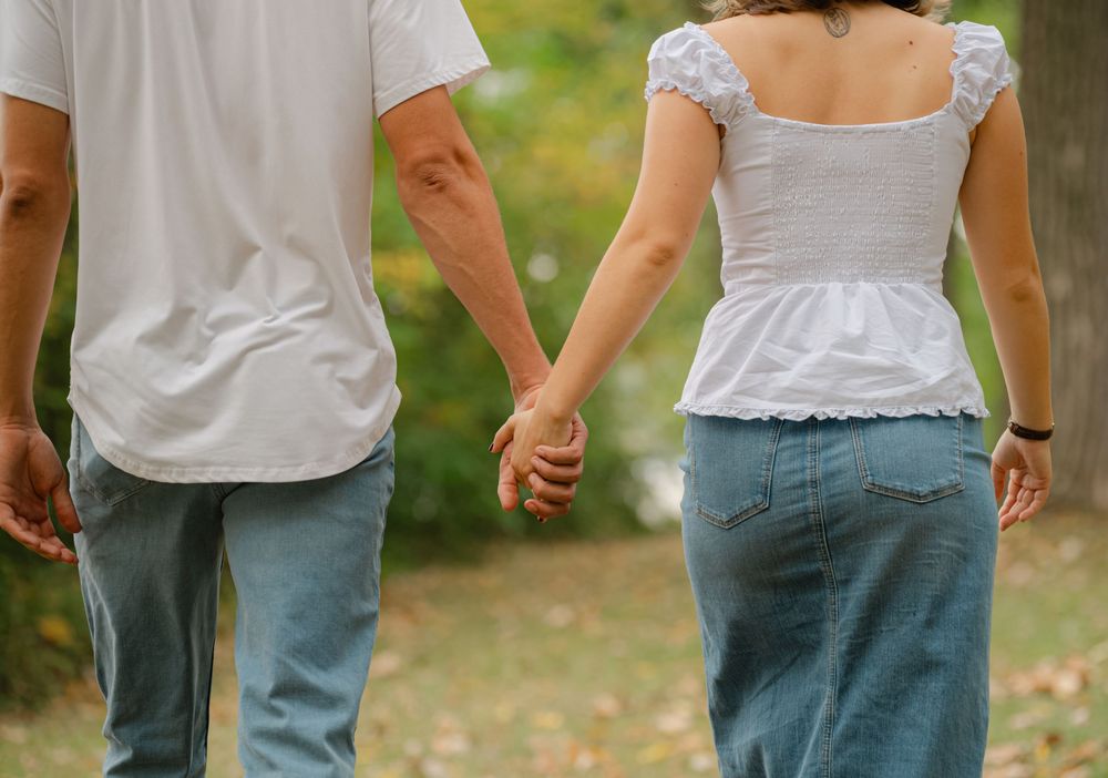 engaged couple holding hands walking away