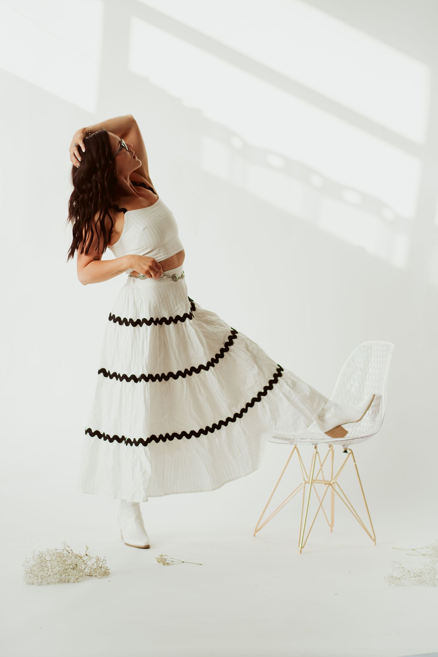 Dancing figure in a white dress with black stripes twirling in sunlit room.